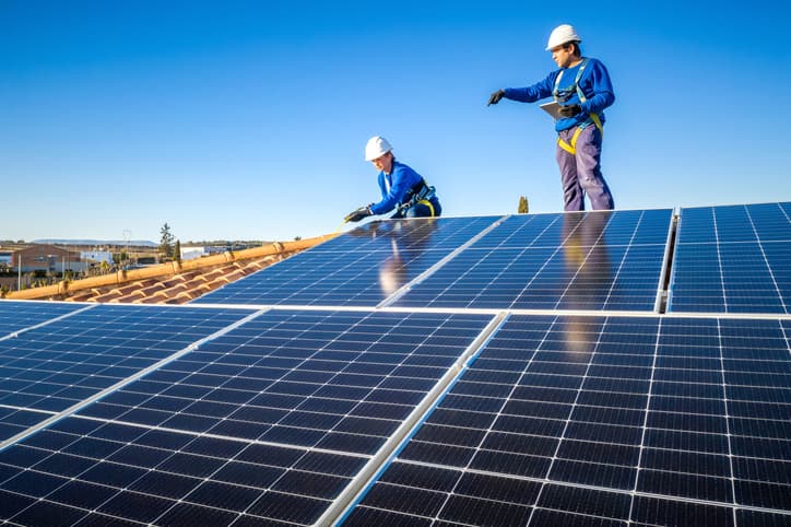 Male and female workers installing solar panels on a roof