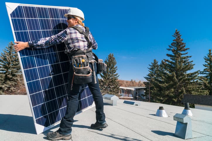 Female technician installing solar panels on a residential homes roof.