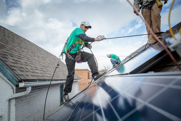 Construction crew installing solar panels on a house.