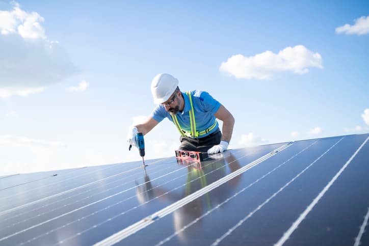 Technician installing solar panels on a bright sunny day