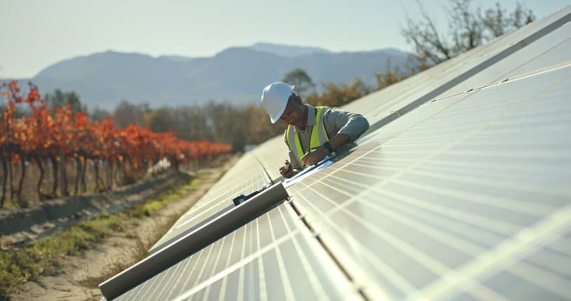 Engineer inspecting solar panels on a slanted roof.