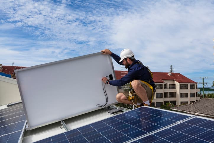 Solar panel technician preparing solar panel connections for operation.